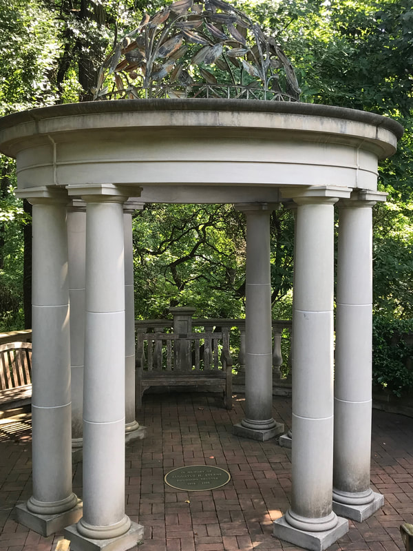 A white marble gazebo looks over a forest